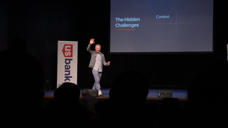 Curt on stage with hand raised