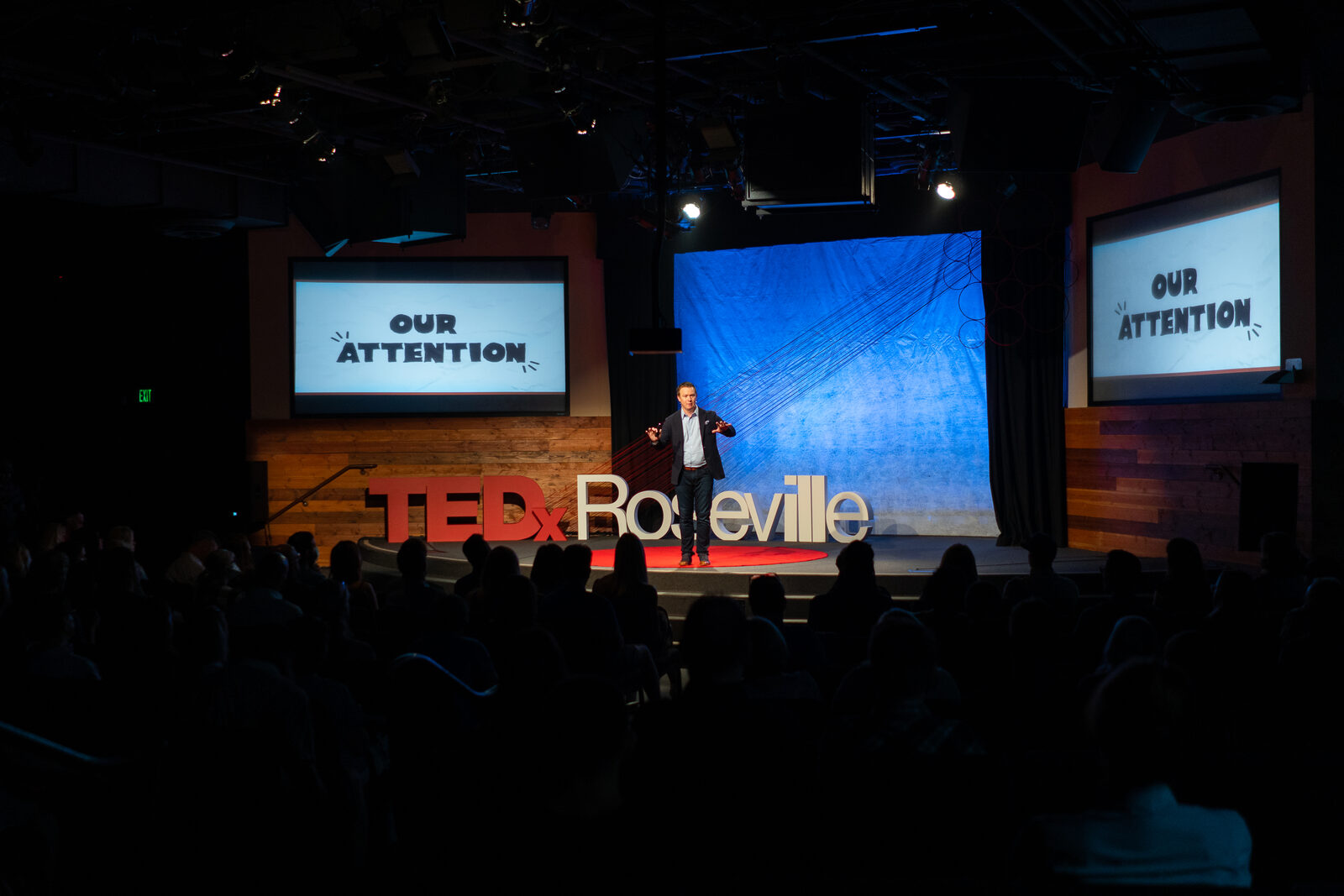 Curt Steinhorst on the TEDxRoseville stage, with Our Attention on the screens.